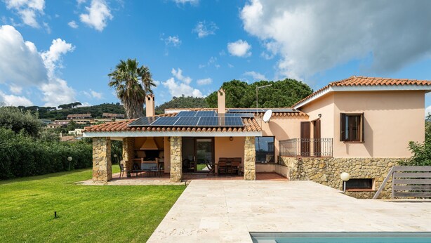 Una casa con piscina, colonne in pietra e un patio.