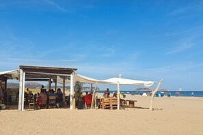 Ett kafé vid stranden med uteservering och utsikt över havet.