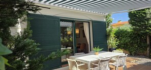 En terrasse med bord og stole, en skydedør og udsigt til indretningen indeni.