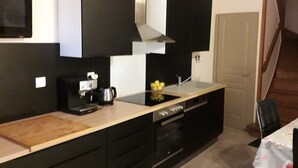 A compact kitchen with a coffee maker, a kettle, and a sink. There is a wooden countertop and a chair visible. - Les Lauriers Roses (Bollène)
