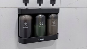 A black wall-mounted dispenser with three bottles labeled shampoo, body wash, and conditioner. - Modern Spacious Retreat with Fast Wi-Fi, Yard & Workspace - 4BR and 2 Full Bath (Waukegan)