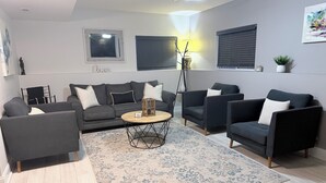 A modern living room with a grey sofa set, a coffee table, and a patterned rug. - Modern Spacious Retreat with Fast Wi-Fi, Yard & Workspace - 4BR and 2 Full Bath (Waukegan)