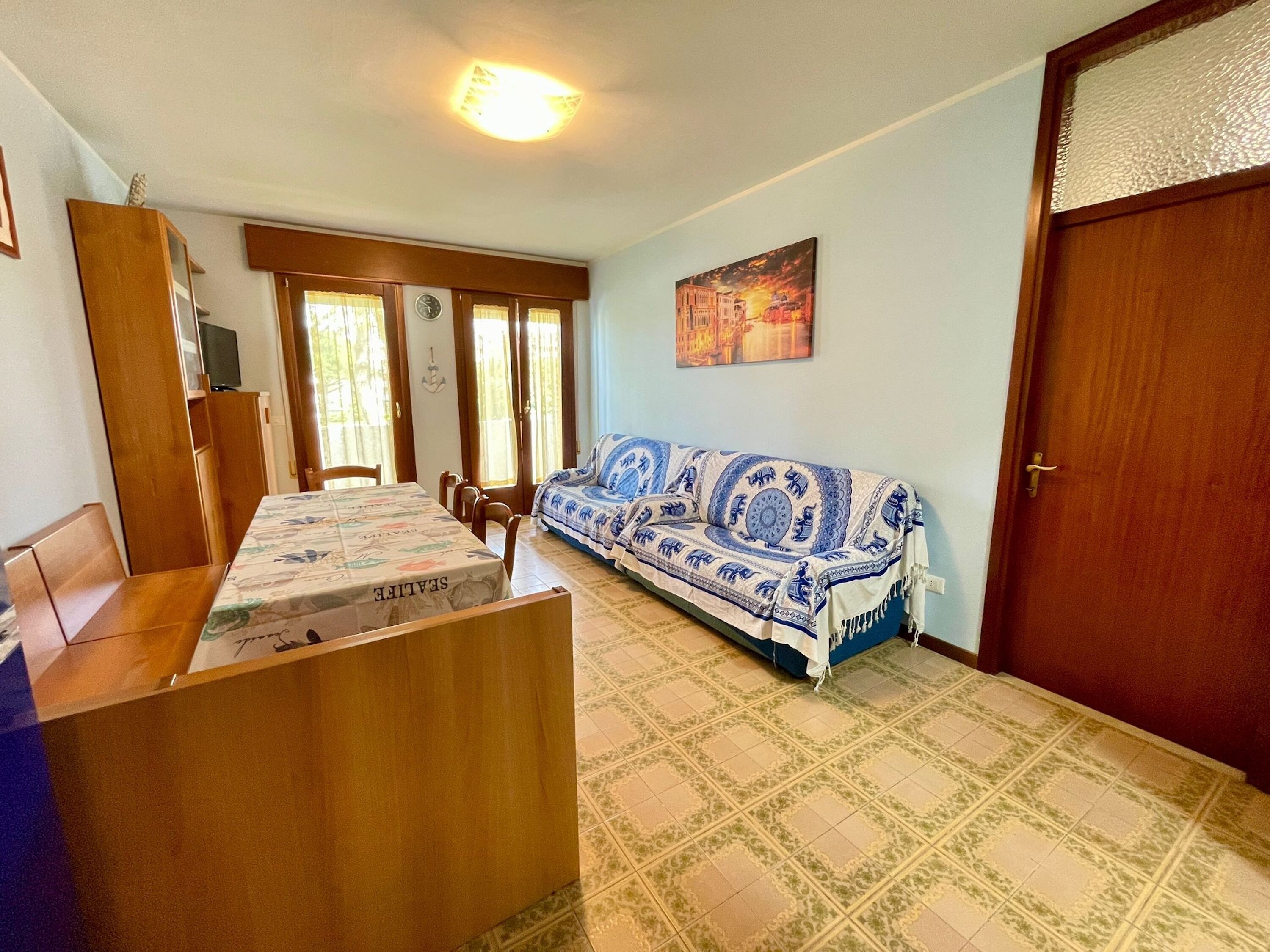 A room with a bed, a sofa, a dining table, and a TV.