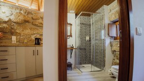 A modern bathroom with a stone wall, a glass shower enclosure, and a toilet. - Refuge of Plenitude (Canelas)