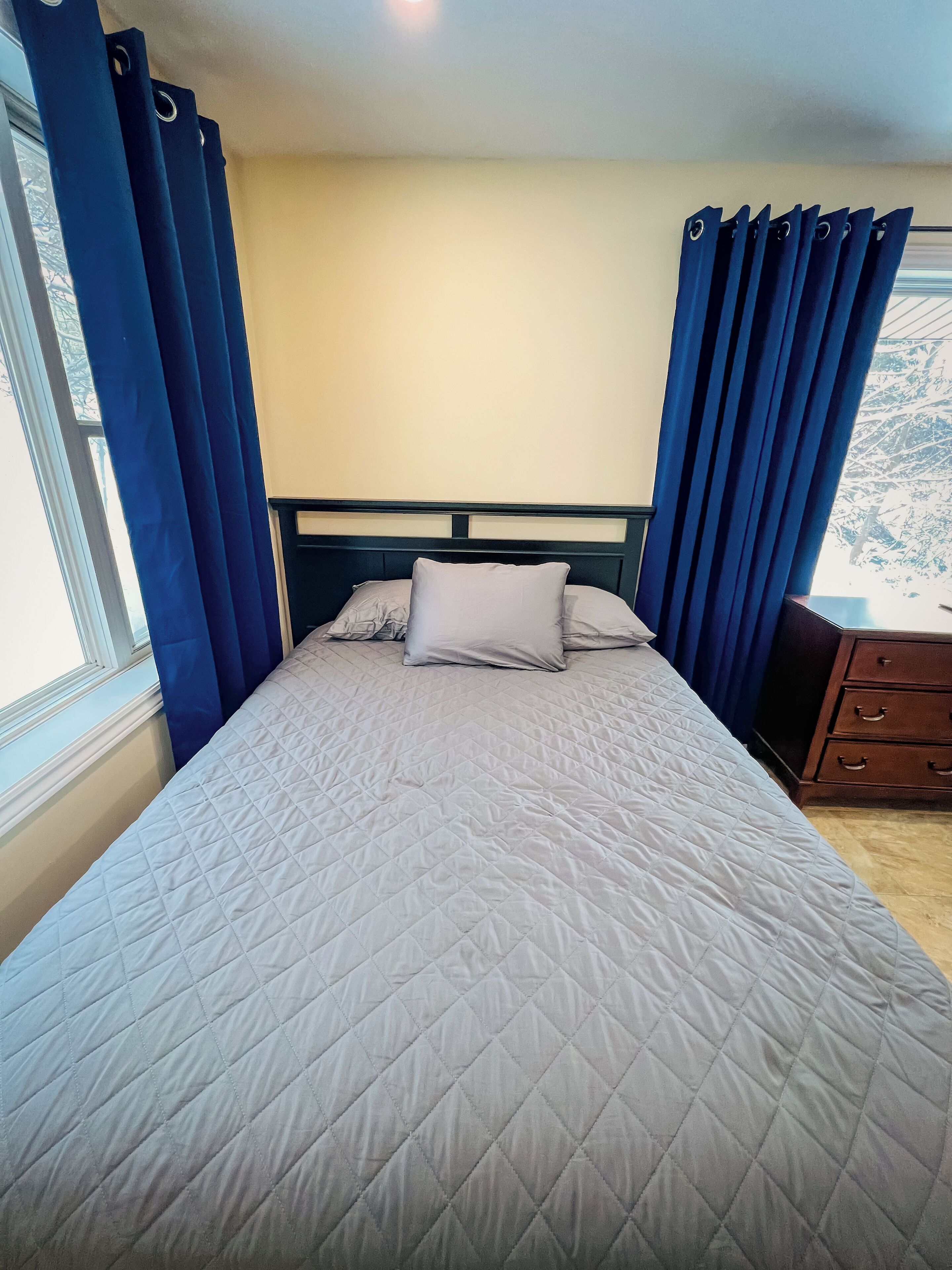 Una cama con cubrecama acolchado, cabecera y mesita de noche con cajones.
