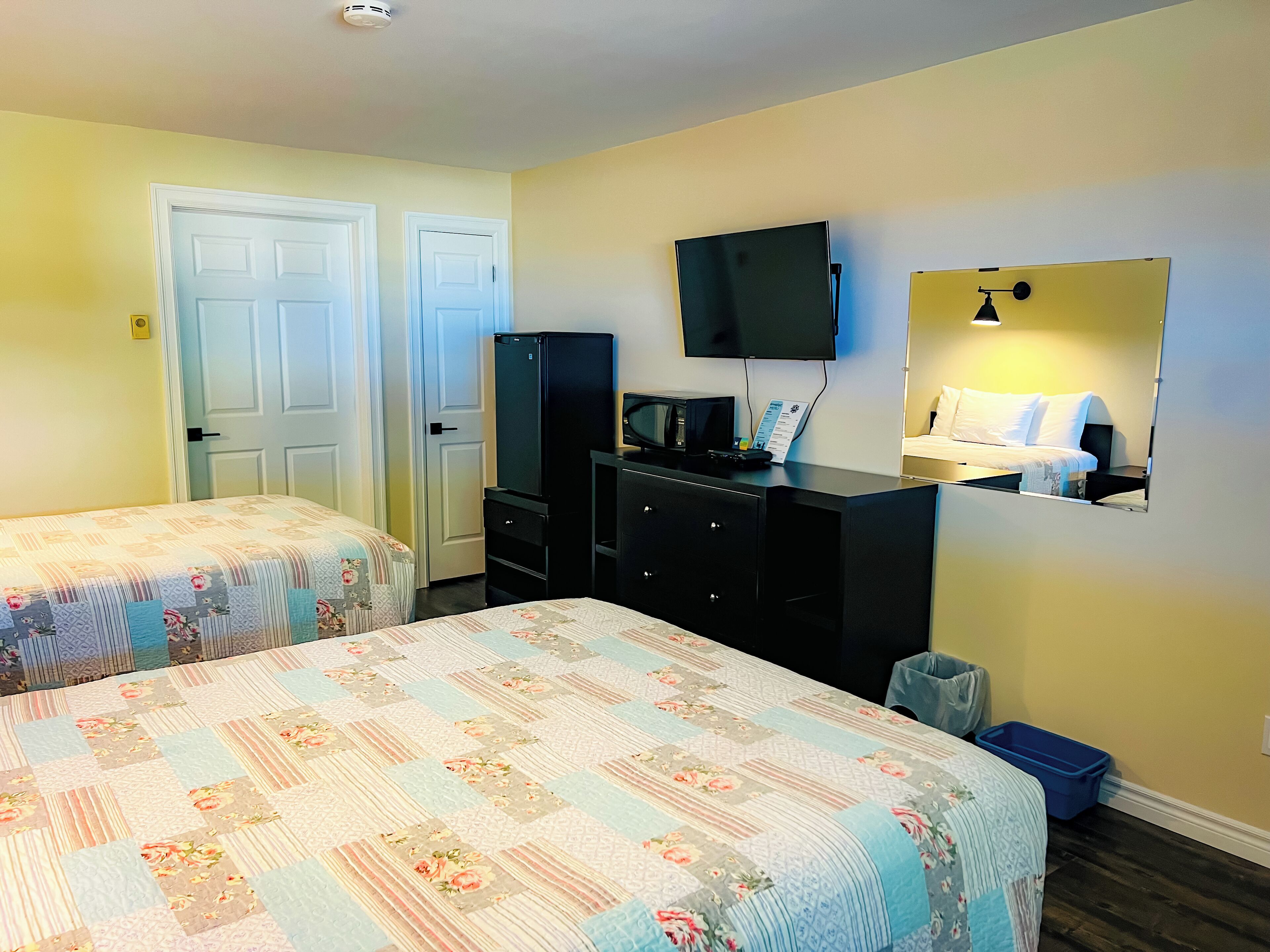 Una habitación de hotel con dos camas, televisión, cómoda y espejo.