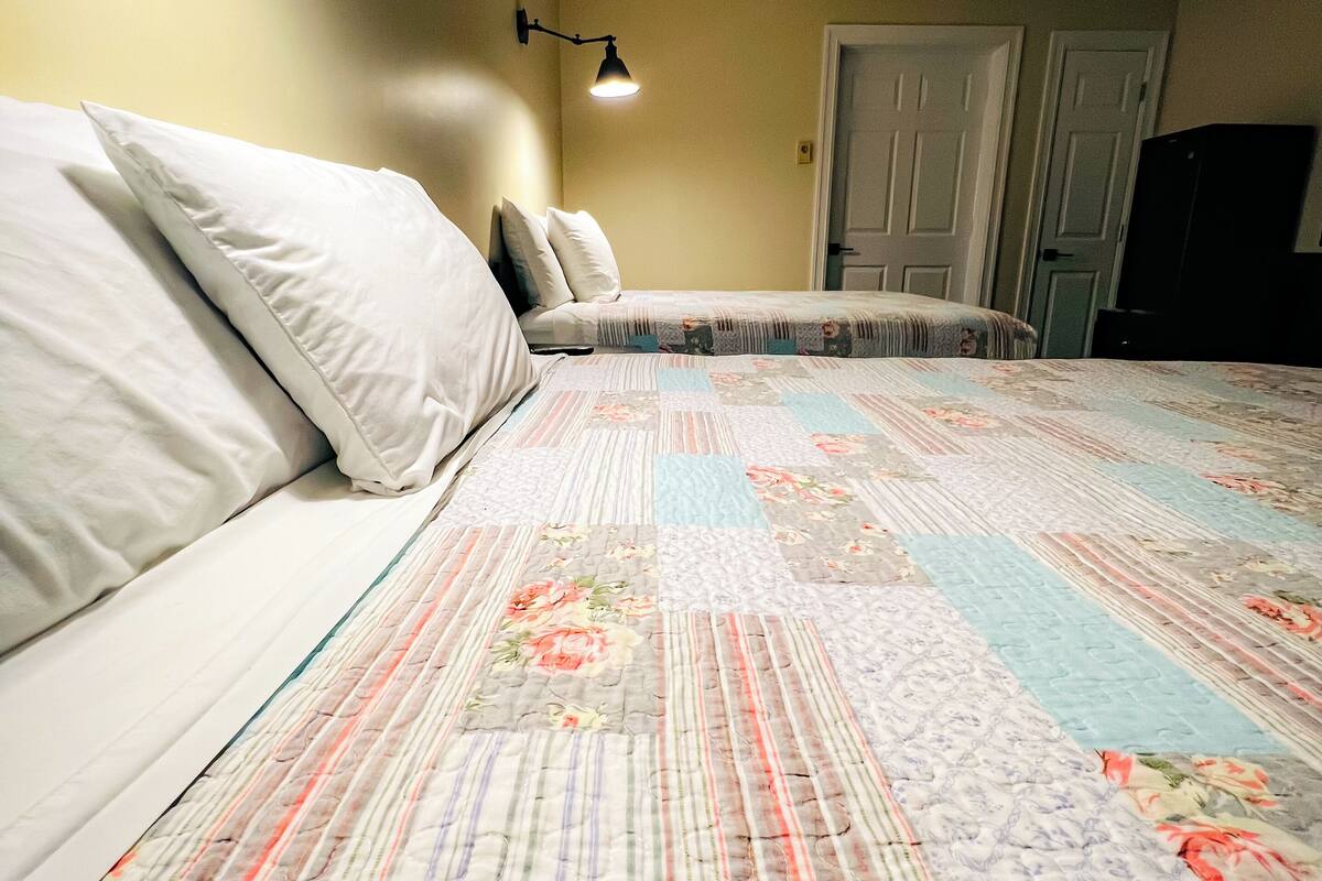 A bedroom with a bed, a nightstand, a lamp, and a door.