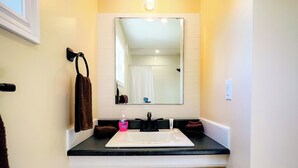 A bathroom with a white vanity, black countertop, and a mirror above the sink.
