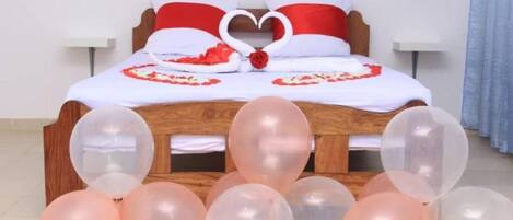 Cama com um arranjo de pétalas de rosa em formato de coração e uma rosa no cobre-leito.