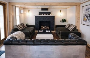 A living room with two sofas, a fireplace, and a large cushioned bench.