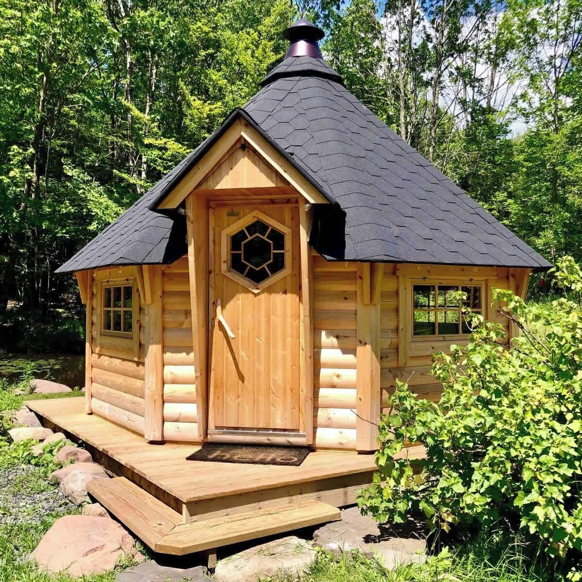 Una cabaña de madera con ventanal hexagonal, una puerta y una chimenea.