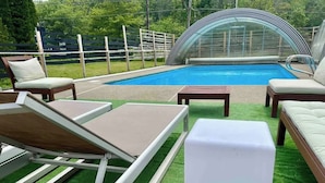 Área de piscina ao ar livre com espreguiçadeiras e uma pequena mesa.