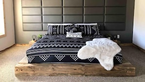 Quarto com cama, cabeceira e janela.