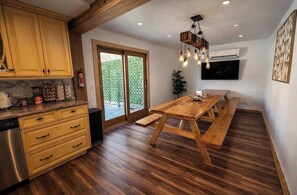 A kitchen with wooden cabinets, a wooden dining table, and a bench.