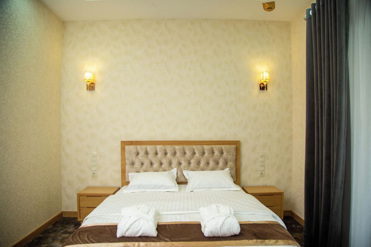 Una habitación de hotel con una cama grande, dos mesitas de noche y dos lámparas de pared.