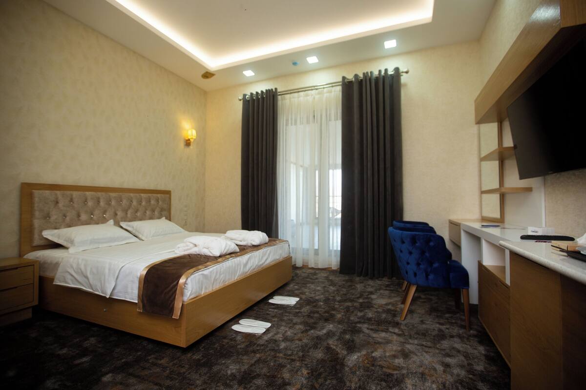 Una habitación de hotel con una cama, un escritorio, una silla y un televisor.