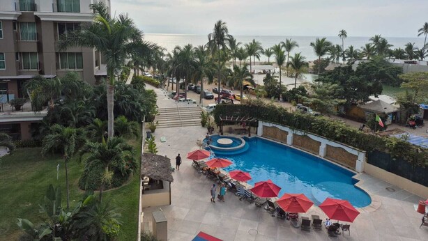 Ein Hotel mit Pool, Palmen und Blick auf den Strand.