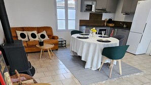 Ein modernes Wohnzimmer mit einem runden Holztisch, einer Couch und einem Essbereich mit Tisch für vier Personen.