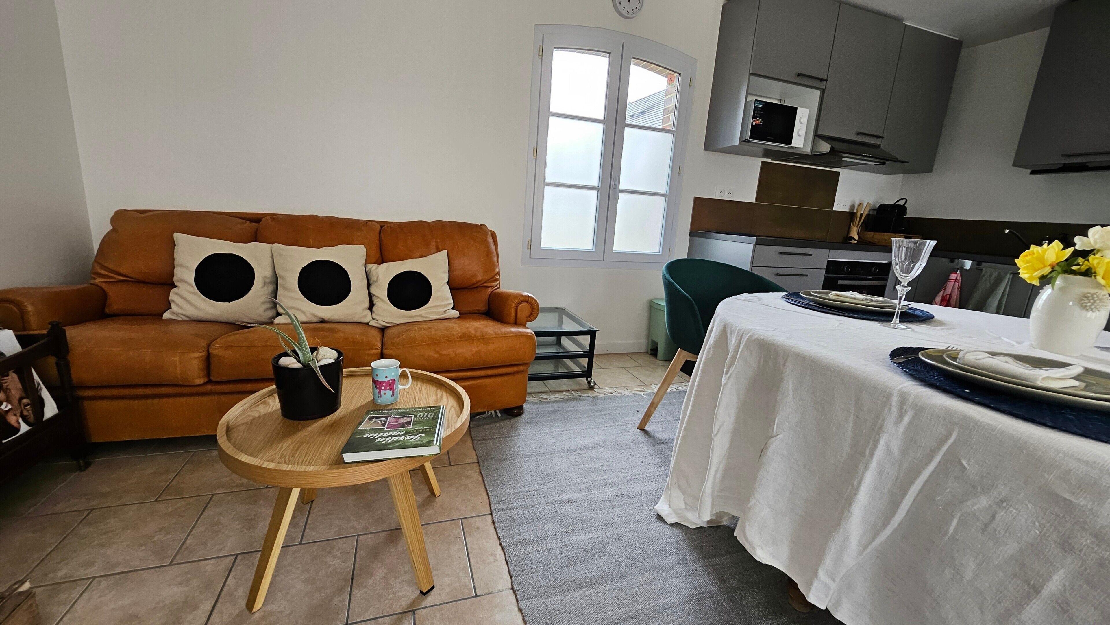 A living room with a sofa, coffee table, and a dining area with a table set for two.