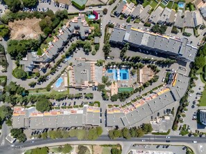 An aerial view of a residential area with multiple buildings, parking lots, and a swimming pool. - Apartment 'Studio On Maria Luisa Beach Wifi' with Shared Pool, Wi-Fi and Air Conditioning (Olhos de Água)