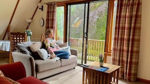 Un salon chaleureux avec un canapé, une table basse et une vue sur un balcon, accessible par une porte-fenêtre coulissante.