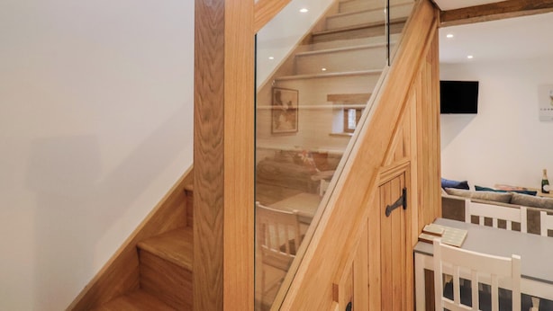 A wooden staircase with glass railings leading to a second floor. - Rose Cottage (Wellington)
