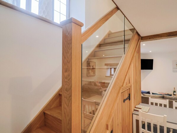 A wooden staircase with glass railings leading to a second floor. - Rose Cottage (Wellington)