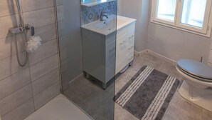 A modern bathroom with a glass shower enclosure, a white sink with a mirror, and a toilet.