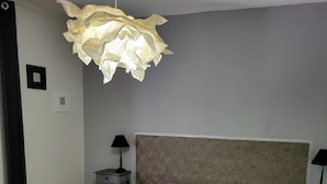 A bedroom with a bed, bedside tables, a hanging light fixture, and a patterned headboard.