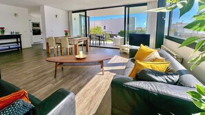 Een moderne woonkamer met een bank, salontafel en eethoek.