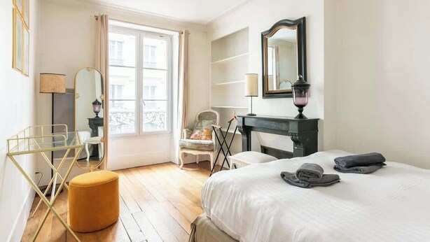 Ein Hotelzimmer mit Bett, Schreibtisch, Stuhl, Fenster und Spiegel.