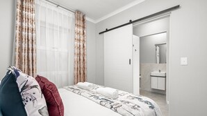 Une chambre à coucher avec un lit, une salle de bain avec un miroir et une porte coulissante.