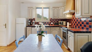 A kitchen with a table, chairs, a refrigerator, an oven, and a microwave. - Cottage for 2 with Heated Pool and Wi-Fi in Quiet Sarlat Setting (Sarlat-la-Canéda)