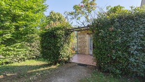 Un sentier de jardin menant à un bâtiment en pierre surmonté d’une pergola.
