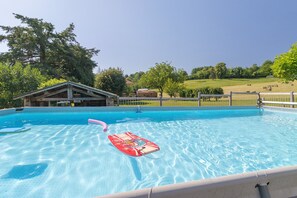 Ein Schwimmbecken mit klarem, blauem Wasser, einem roten Schwimmer und einem Holzgebäude im Hintergrund.