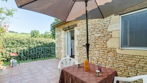 Une terrasse avec une table, des chaises et un parasol.