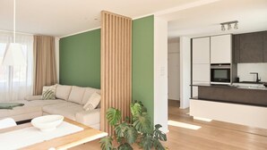 Ein modernes Wohnzimmer mit einer Eckcouch, einem Esstisch mit einer Schüssel und einer grünen Akzentwand.