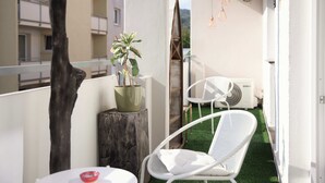 Ein Balkon mit einem weißen Stuhl, einem Topfpflanzen und einem hölzernen Baumstumpf.