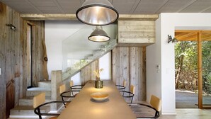A modern dining area with a long table, chairs, and a central vase. - Holiday Home “Loft 2 – Sea View with Pool”, Wi-Fi and Air Conditioning (Porto-Vecchio)