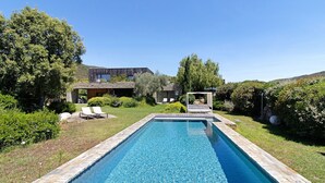 A rectangular swimming pool with stone edging, surrounded by a grassy area and trees. - Holiday Home “Loft 2 – Sea View with Pool”, Wi-Fi and Air Conditioning (Porto-Vecchio)