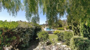 A garden with a swimming pool, surrounded by dense foliage and a clear sky. - Holiday Home “Loft 2 – Sea View with Pool”, Wi-Fi and Air Conditioning (Porto-Vecchio)