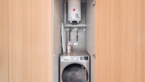 Een kleine wasruimte met een wasmachine, een droger en een boiler.