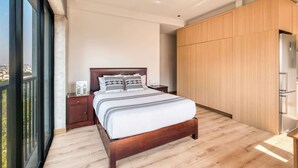 Een moderne slaapkamer met een groot bed, houten vloeren, een nachtkastje en een kledingkast.