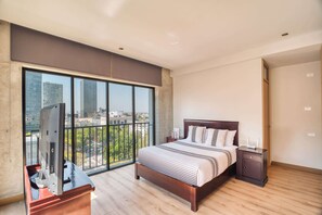 Une chambre moderne avec une grande fenêtre, un lit, une table de chevet et un téléviseur.
