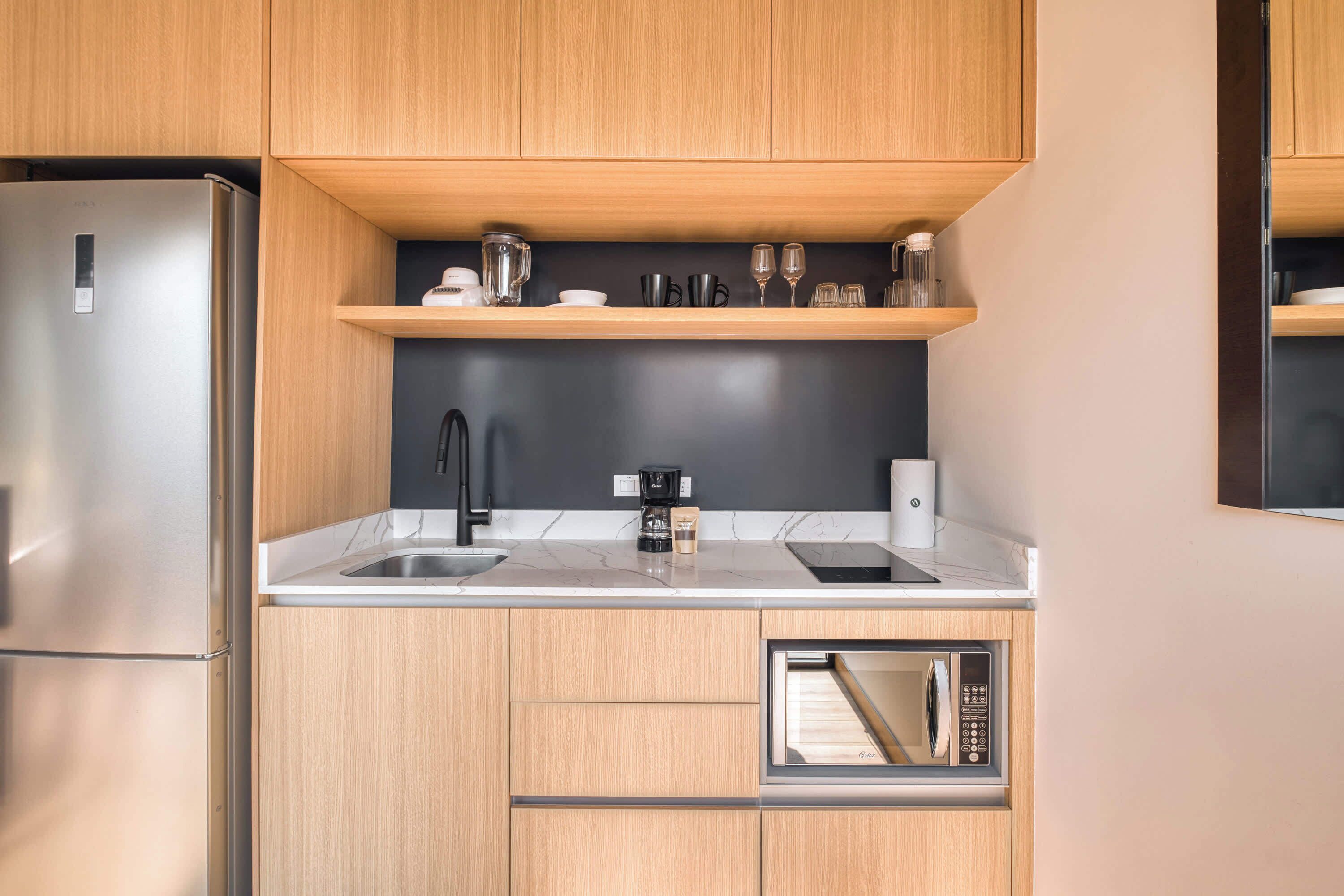 Una cocina moderna con armarios de madera, un refrigerador de acero inoxidable, un microondas empotrado y una cafetera.