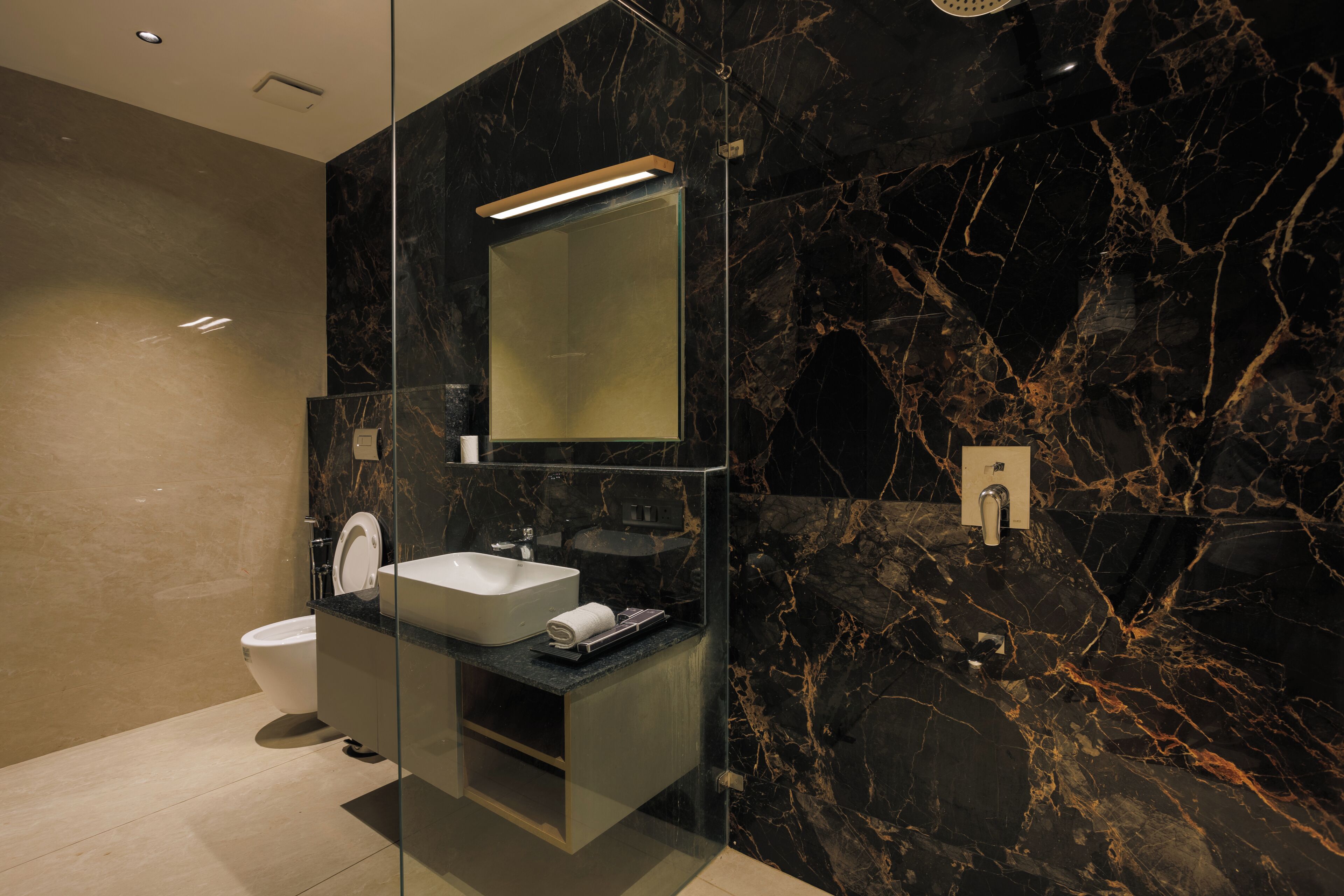 A modern bathroom with a glass-enclosed vanity, a white sink, and a large mirror.