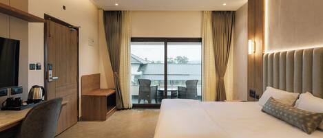 A hotel room with a bed, a desk, a chair, a television, and a balcony with curtains.