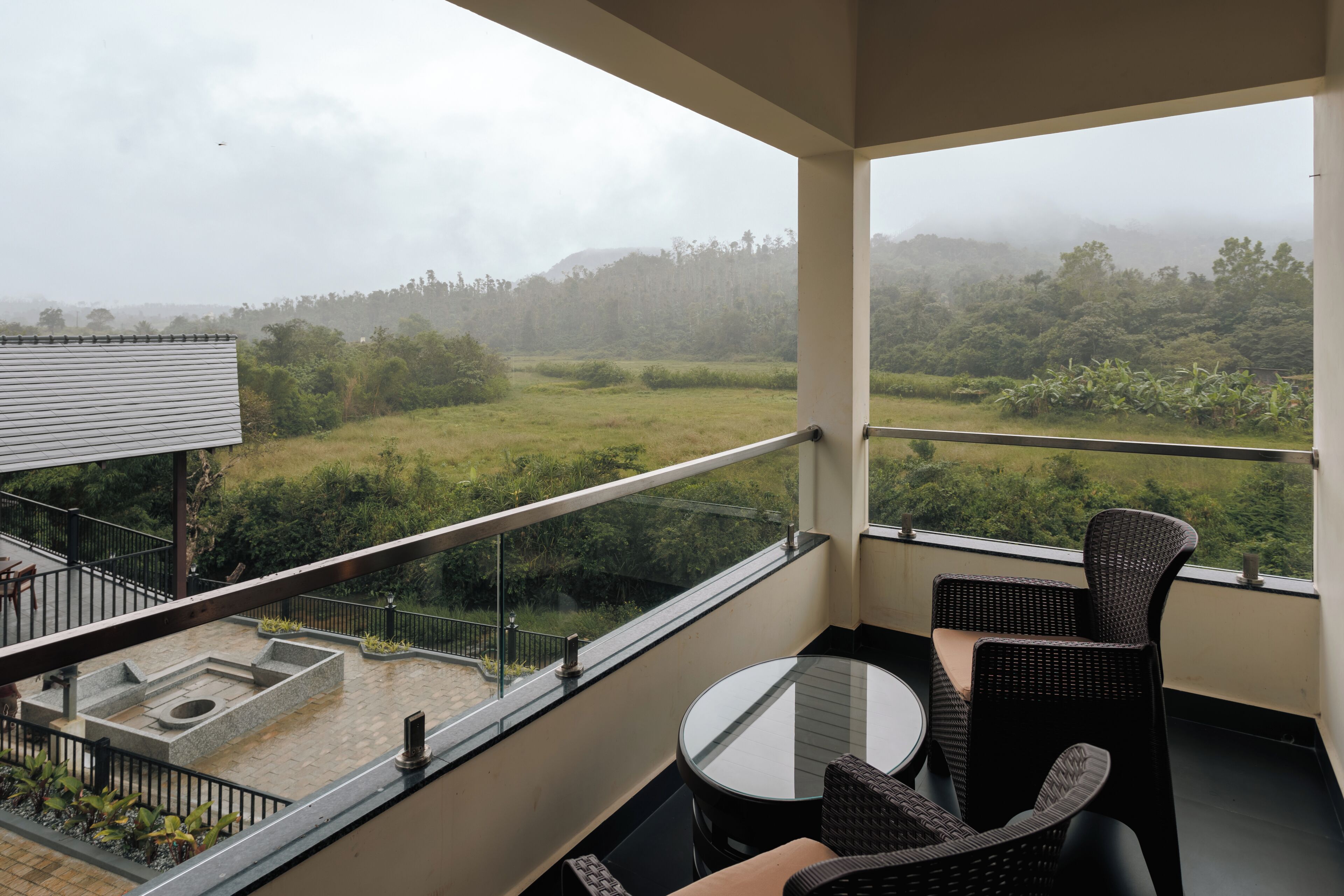 Un balcón con vistas a un paisaje verde y una cadena montañosa distante.