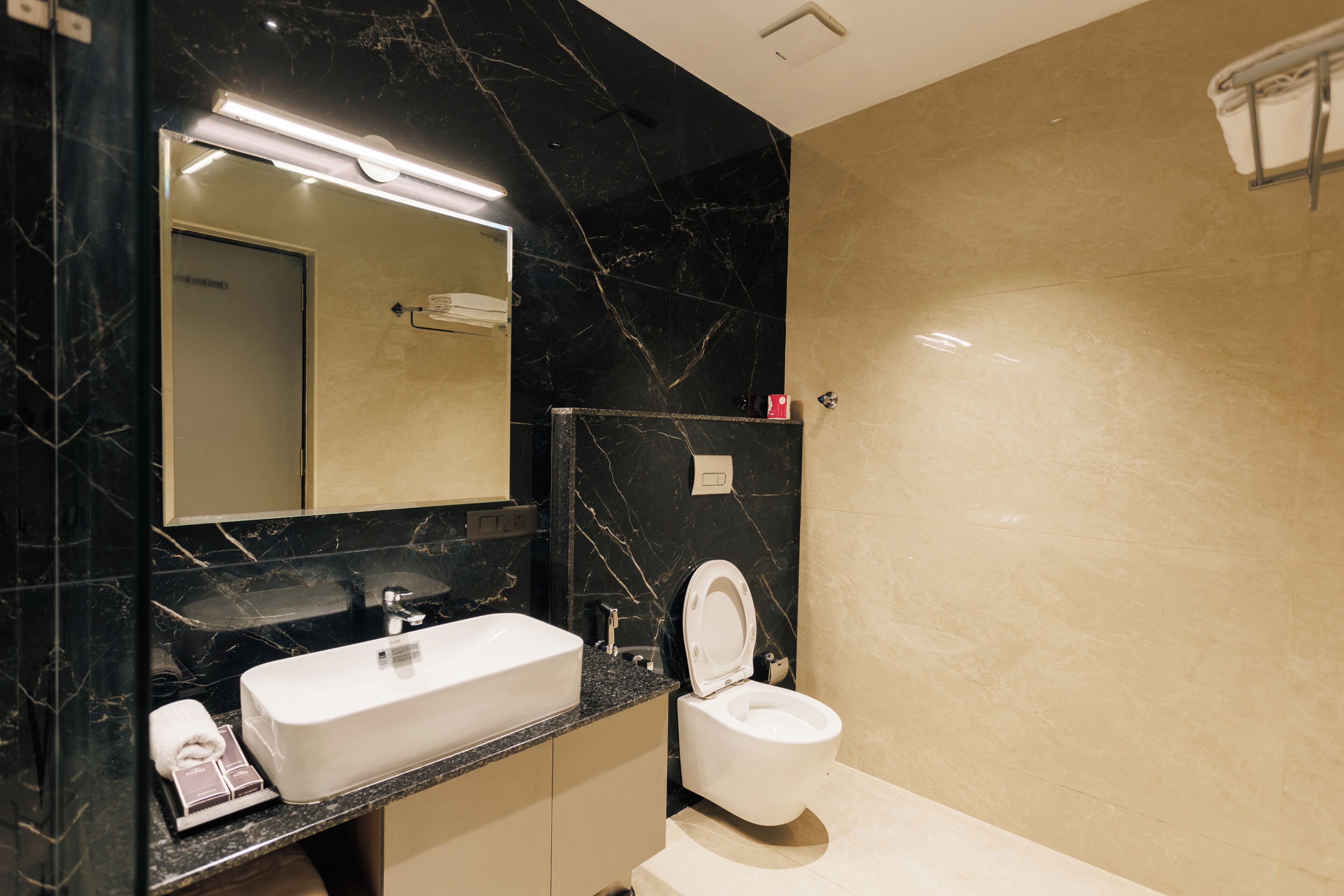 A modern bathroom with a marble sink, a toilet, and a mirror.