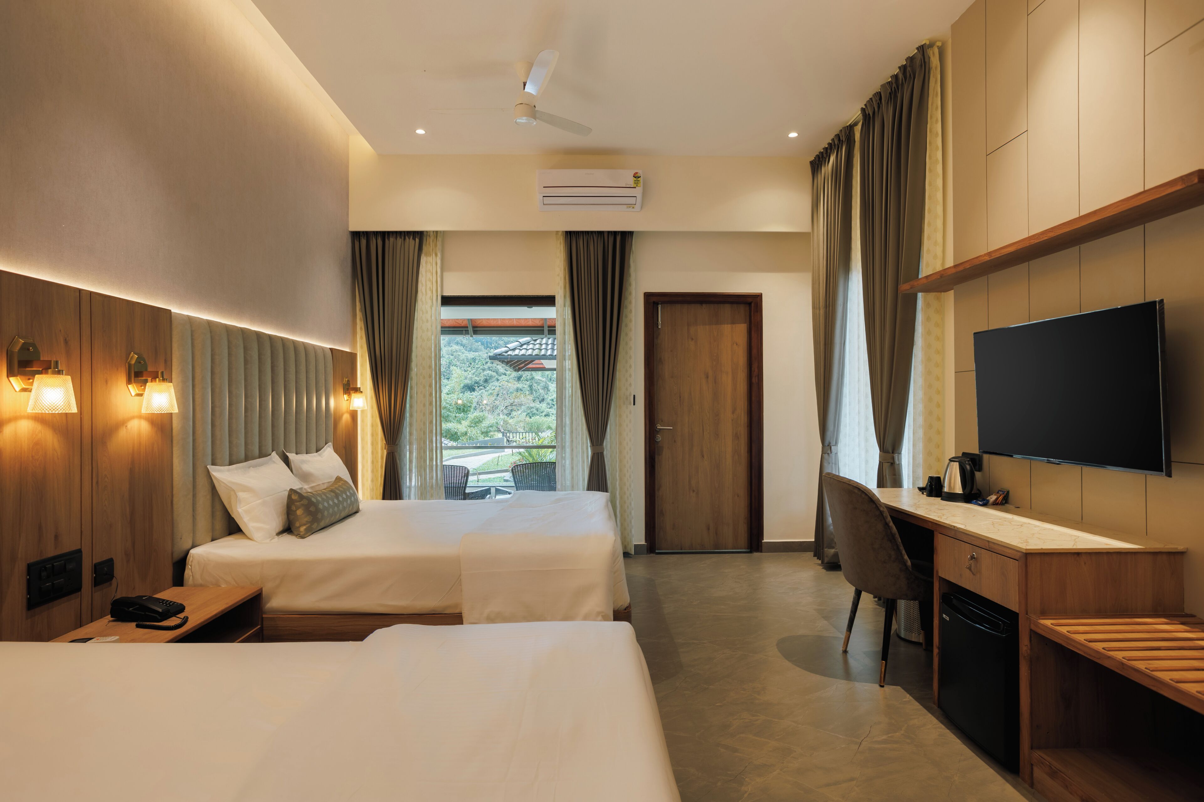 Une chambre d’hôtel avec deux lits, un bureau, une chaise, une télévision et un appareil de climatisation.